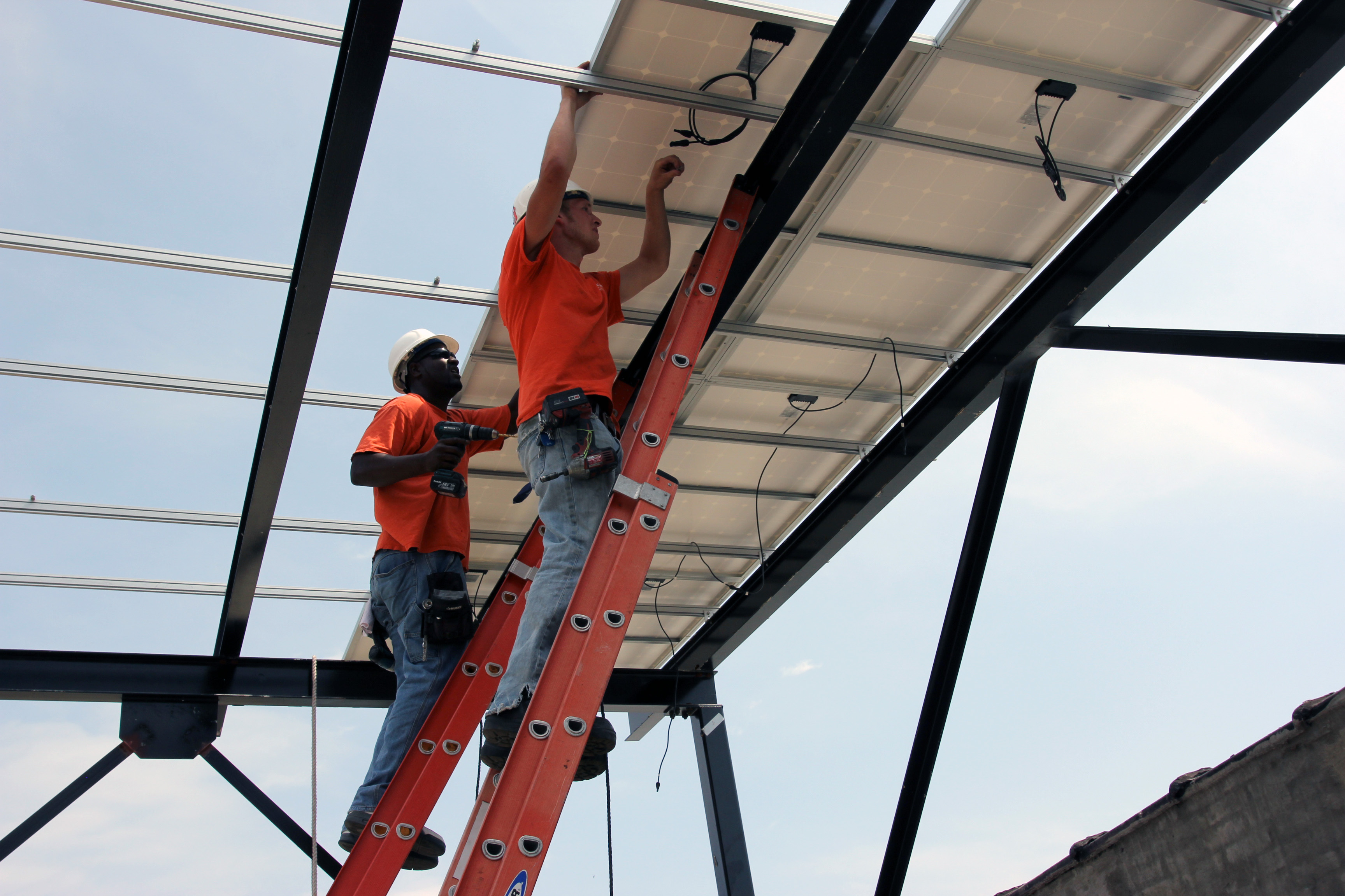 Solar installers Paul and Terry securing solar panels to the canopy's rackking